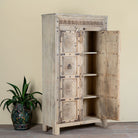 Wooden cabinet Elayna with intricate carvings on a beige wall background