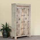 Side angle image of a reclaimed teak wood cabinet Elayna featuring an antique Indian door with carved motifs and iron accents. A unique piece of old door furniture in Mediterranean style, offering practical storage and historic charm.