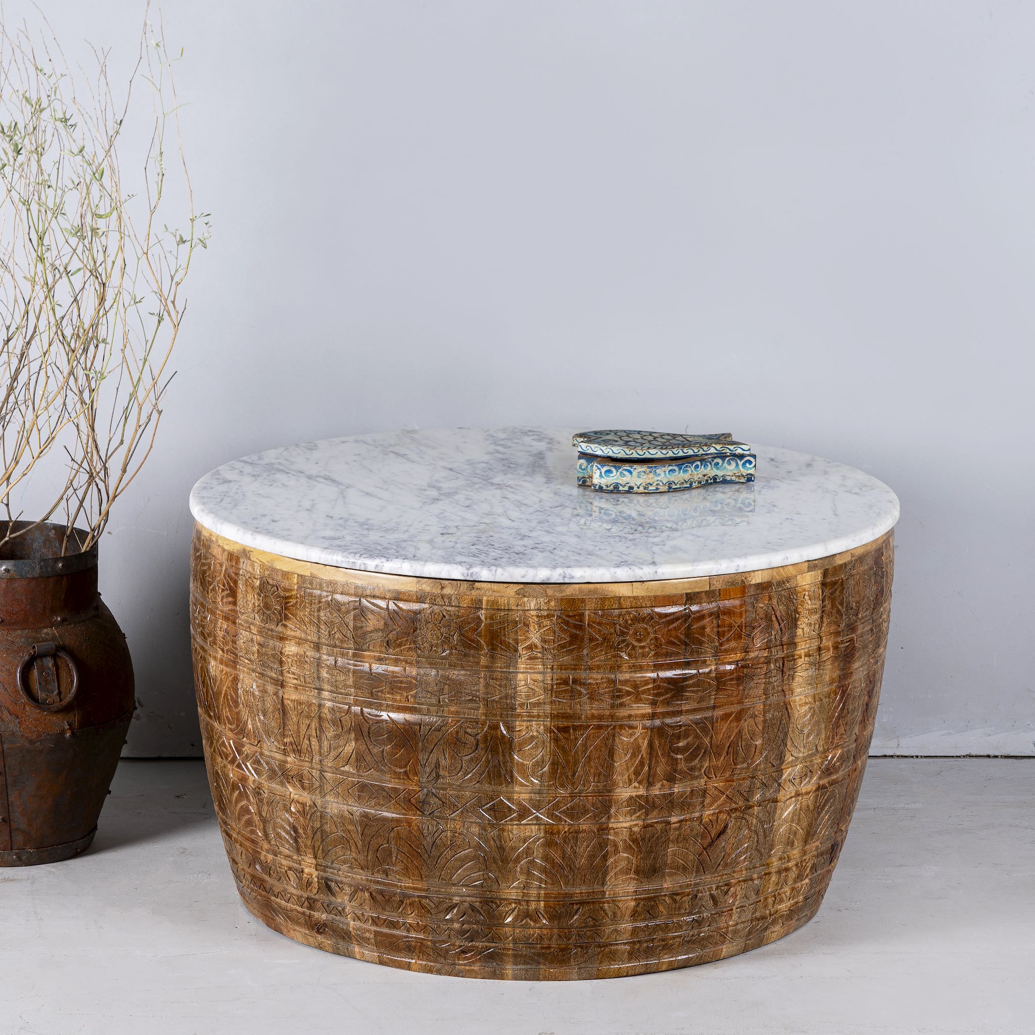 Image with a round hand carved mango wood coffee table with a white marble top.