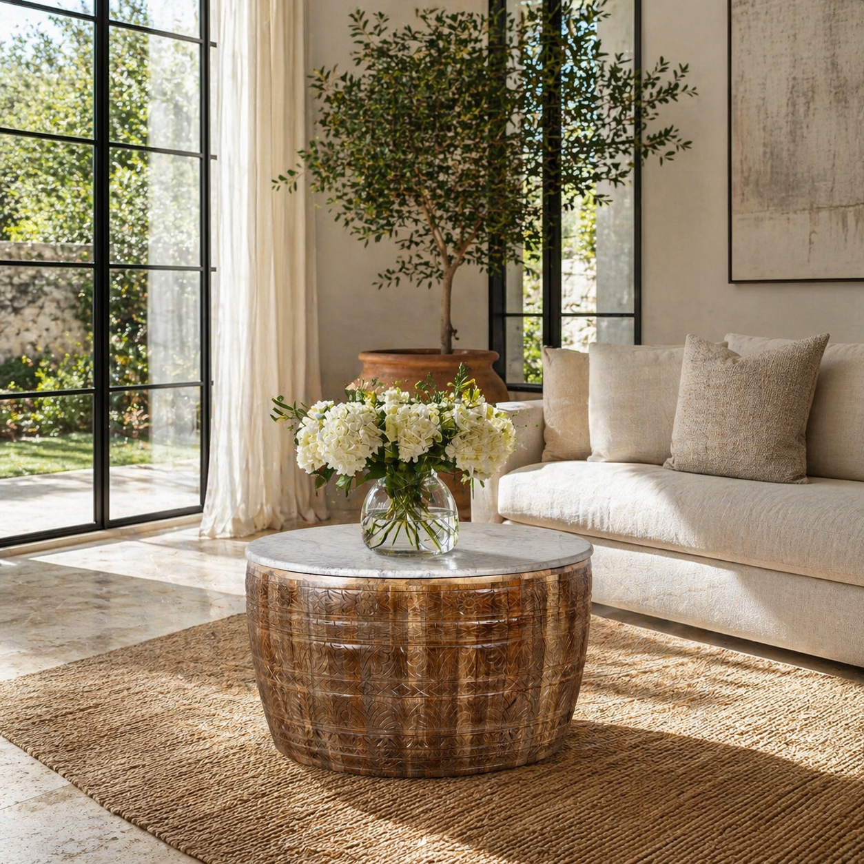 Lifestyle image with a round hand carved mango wood coffee table with a white marble top.