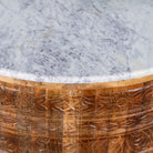 Close up image of a round hand carved mango wood coffee table with a white marble top.