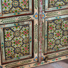 Close up image of a reclaimed wood cabinet with floral and geometric designs, perfect for a bohemian interior with Mediterranean style.