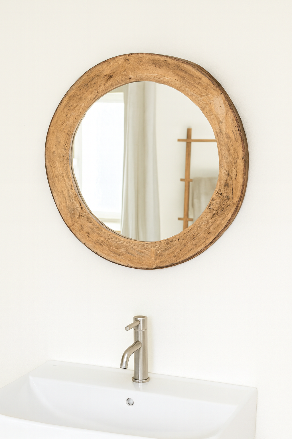 Lifestyle imagination of a round carved wooden mirror with reclaimed teak frame and rustic iron edging; Indian furniture online, 110 cm diameter, 8 cm deep.