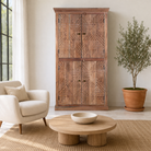 Lifestyle image of a hand crafted acacia wood cabinet with 4 doors, brass fitted door knobs and geometrical carvings.