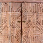 Close up view of a hand crafted acacia wood cabinet with 4 doors, brass fitted door knobs and geometrical carvings.