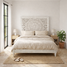 Lifestyle image of a hand-carved wooden bed made of mango wood with large floral panel in white finish – Flair model by Om Home & Garden