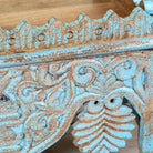 Close up image of a hand carved mango wood wall shelf with distressed vintage finish, 90cm.