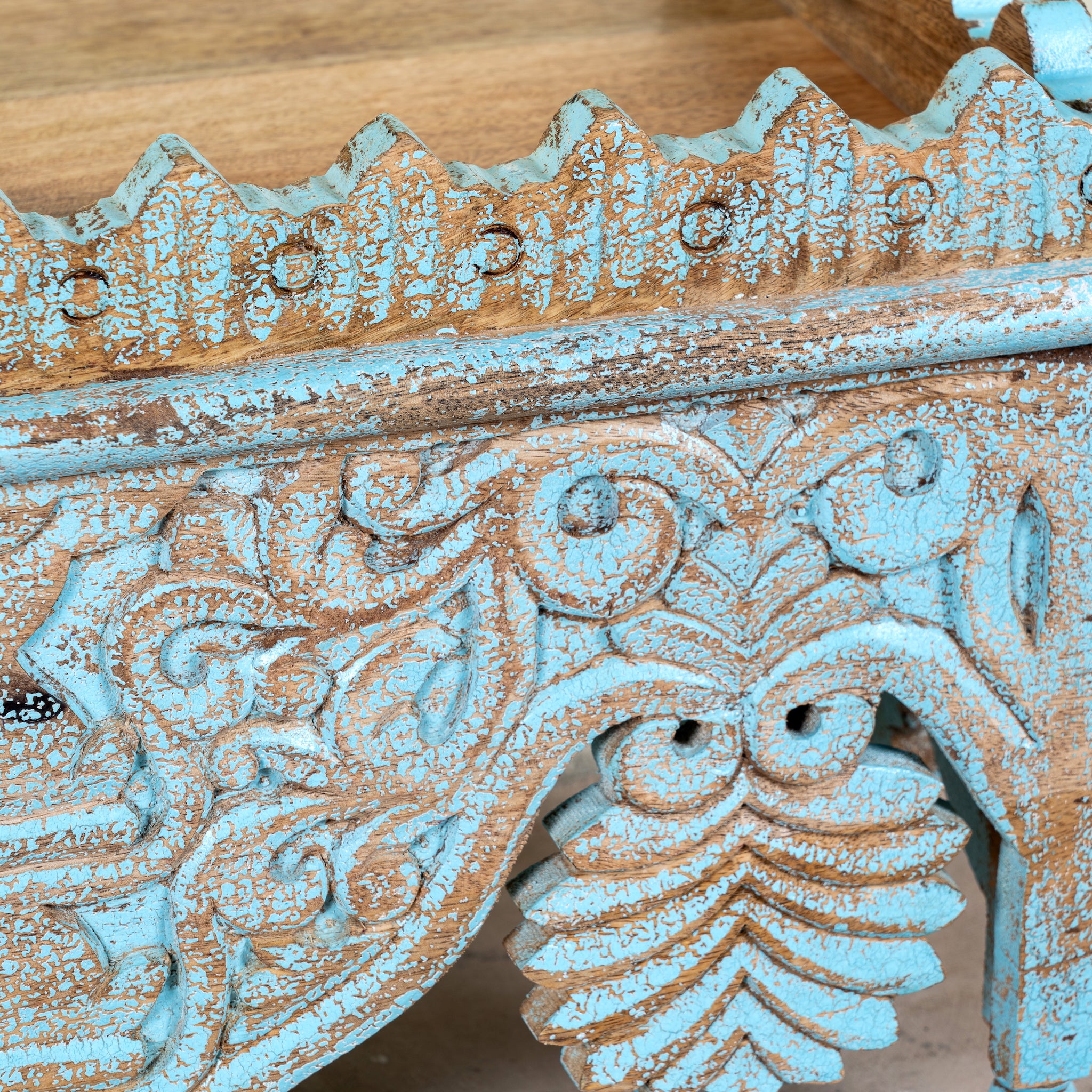Close up image of a hand carved mango wood wall shelf with distressed vintage finish, 90cm.