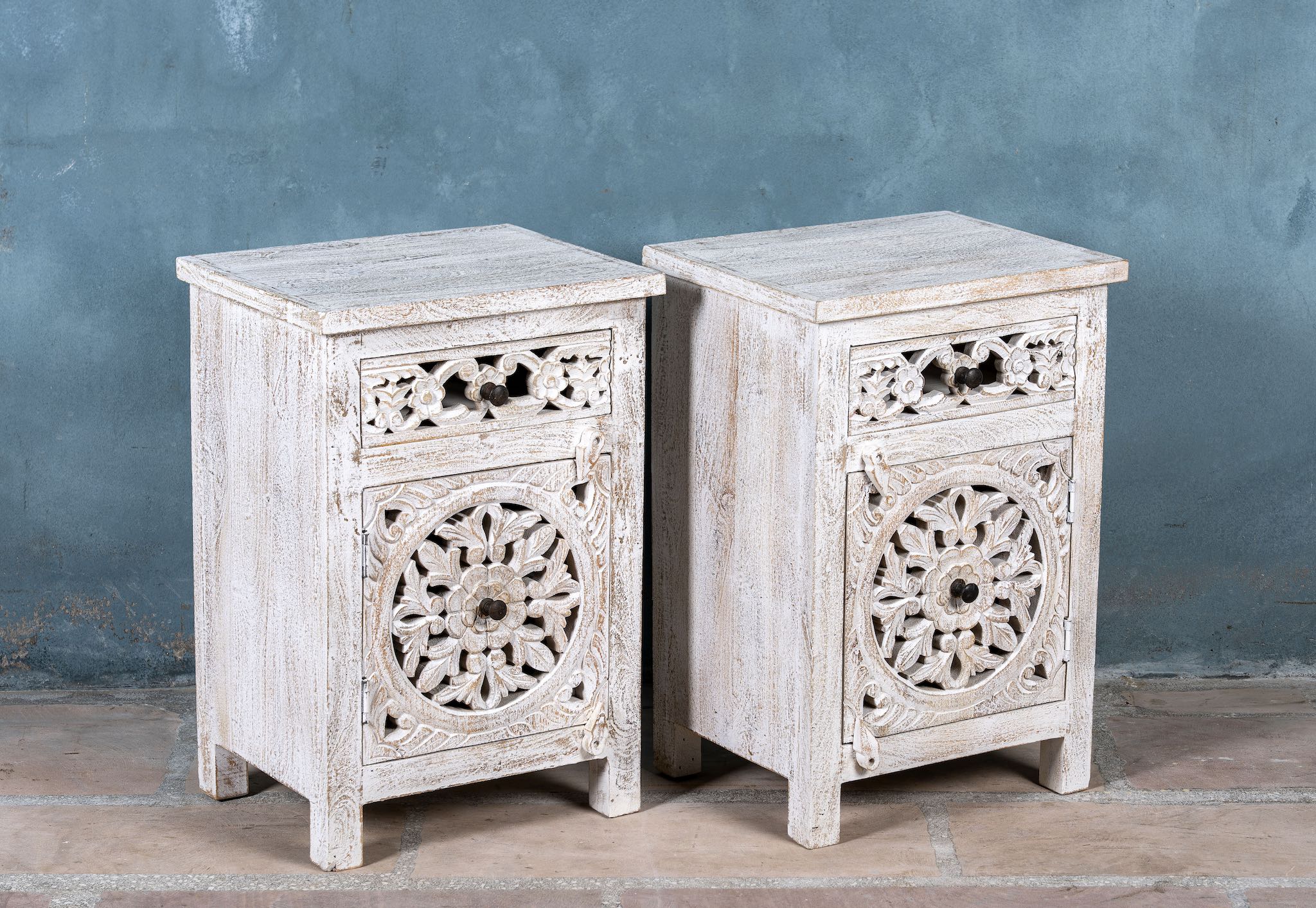 Side angle image of a Whitewashed nightstand made of mango wood with Mediterranean-style carved detailing and one drawer – Gagan bedside table by Om Home & Garden