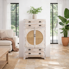 Lifestyle image of a handcrafted mango wood cabinet with rattan doors and carvings, living room furniture in whitewashed finish, 80 × 148 × 40 cm.