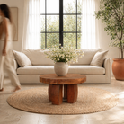 Lifestyle image of a rustic wood coffee table with round reclaimed teak top and black charred finish; sustainable furniture, 70 cm diameter, 40 cm height.
