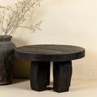 Front view of a rustic wood coffee table with round reclaimed teak top and black charred finish; sustainable furniture, 70 cm diameter, 40 cm height.