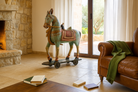 Lifestyle image of a large hand-painted Indian wooden horse sculpture on wheels – Rajasthani mango wood decor piece, ideal as artistic Indian home accessory, 110x90x30cm.