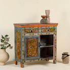 Side angle image with open door of a hand painted cabinet made of reclaimed wood with ornate floral design in vintage style.