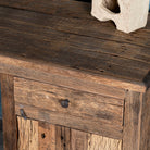 Close up image of a rustic minimalist wooden desk made from reclaimed old wood with drawer and cabinet, 130 × 60 × 75 cm.