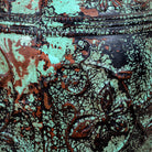 Close up image of a hand-painted clay vase with vintage distressed turquoise finish, raised floral relief pattern and rounded silhouette, 35cm.