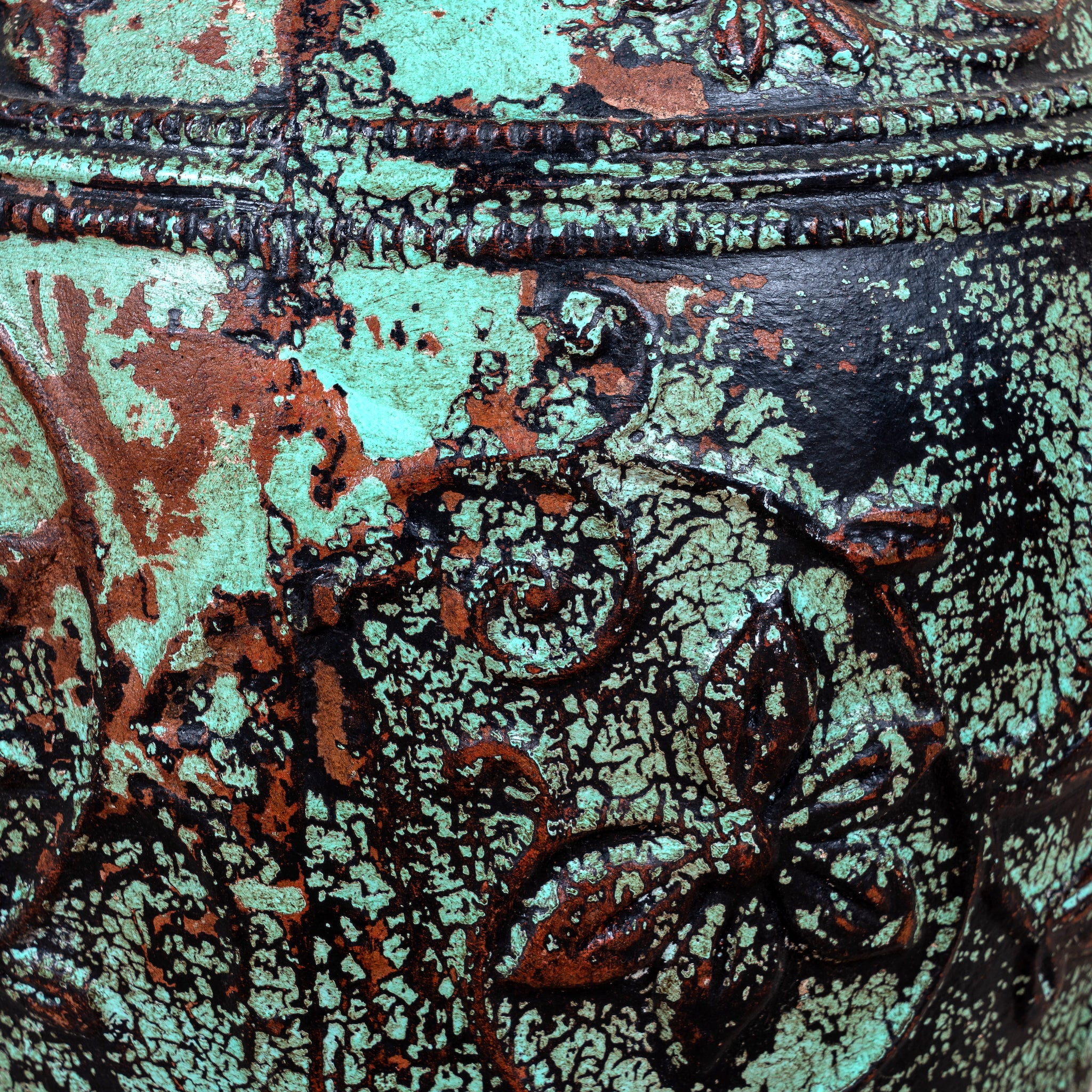 Close up image of a hand-painted clay vase with vintage distressed turquoise finish, raised floral relief pattern and rounded silhouette, 35cm.