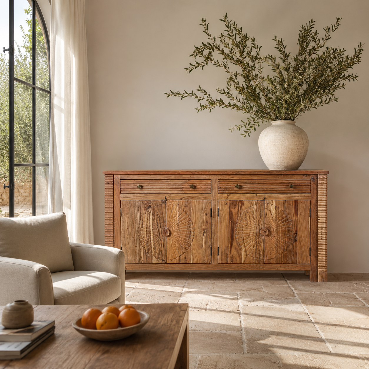 Lifestyle image of a carved acacia wood sideboard with four doors, two drawers, brass handles, and tapered legs; artisanal acacia wood furniture, 180 × 40 × 90 cm.