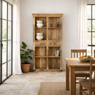 Lifestyle image of a handcrafted mango wood bookshelf with carved detailing – mango wood shelving and carved wooden furniture in a warm brown finish for timeless interiors.