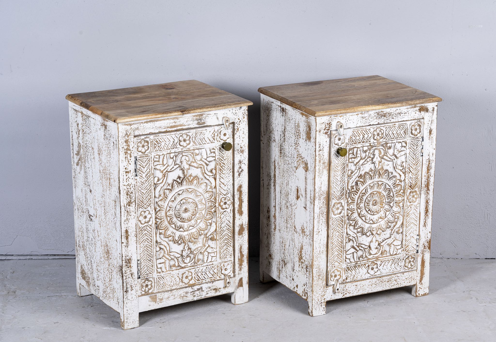 Side angle image with open door of a set of two hand carved bedside tables with mandala and floral motifs; reclaimed wood in white washed furniture style, 50 × 40 × 72 cm.