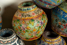 Close up image of hand-painted papier-mâché vases from India with floral folk-art designs in vibrant mixed colors. Unique Indian decor and decorative art objects handcrafted using traditional methods.