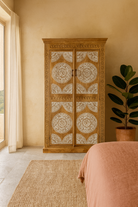 Lifestyle imagination of a carved wood furniture wardrobe made from mango wood with whitewashed floral doors, wooden wardrobe in Ibiza-inspired style, 100 × 40 × 180 cm.