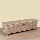Side angle image of a Harivansh hand carved mango wood chest with floral design and distressed vintage finish 180cm