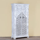 Side angle image of a white-washed hand-carved wooden wardrobe made of solid mango wood, vintage furniture with Mediterranean Ibiza style, 180 × 90 × 40 cm.