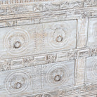 Close up image of a handcrafted chest of drawers Hemali made from reclaimed wood, featuring four carved drawers with circular motifs and a whitewashed finish. A rustic, sustainable furniture piece with soft texture and elegant detailing.