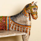 Close up image of the head of a hand-painted reclaimed wood chair-style horse bench with double carvings; unique furniture for a bohemian interior, 160 × 70 × 90 cm.