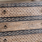 close up image of a hand painted beige-black wooden chest of 5 drawers in vintage style.