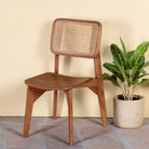 Side angle image of an acacia wood chair with woven rattan backrest and solid wooden frame; wooden armchair for dining or living rooms, 45 × 45 × 85 cm.