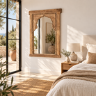 Lifestyle image of a Ishvank reclaimed teak wood mirror made from an old Indian window frame with carved details and arched opening, 87x115cm