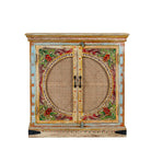 White background image of a hand-painted, hand-carved cupboard made of mango wood with floral design and rattan inserts.