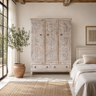 Lifestyle image of a hand carved creme colour mango wood wardrobe wit 2 drawers and 4 shelfs and ample storage.