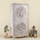 Side angle image of a white washed armoire with hand-carved Tree of Life motif, mango wood carved wood furniture with storage, 90 × 40 × 180 cm.
