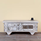 Janash whitewashed mango wood coffee table chest with decorative iron fittings and wooden wheels 116cm