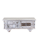 White background image of a Janash whitewashed mango wood coffee table chest with decorative iron fittings and wooden wheels 116cm