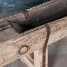 Close up picture of an antique console table repurposed from reclaimed teak wood feeding trough with carved details and iron fittings; unique furniture ideal for rustic interiors, compatible with teak wood benches, 234 × 31 × 61 cm.