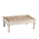 White background image of a Jayson reclaimed teak wood coffee table with glass top, removable legs, and hand carved antique Indian ceiling panel.