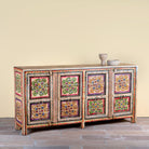 Side angle image of a boho style hand painted sideboard with reclaimed old Indian door decoration. Unique cabinet with floral design.