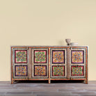 Decorative wooden sideboard with colorful floral patterns on a beige wall background