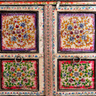 Close up image of a boho style hand painted sideboard with reclaimed old Indian door decoration. Unique cabinet with floral design.
