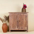 Carved acacia wood cupboard with floral cutout doors and brass knobs, 90 × 40 × 90 cm.