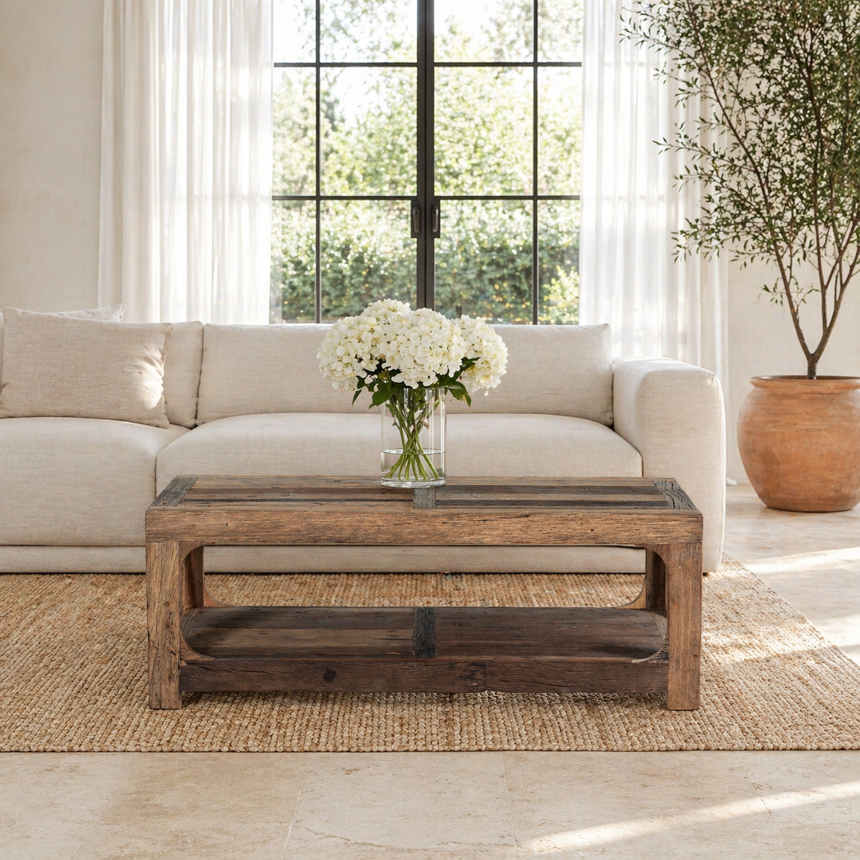 Lifestyle image of a driftwood coffee table made from reclaimed wood with rustic finish and open lower shelf; sustainable furniture, 120 × 60 × 40 cm.