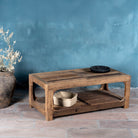Side view of a driftwood coffee table made from reclaimed wood with rustic finish and open lower shelf; sustainable furniture, 120 × 60 × 40 cm.
