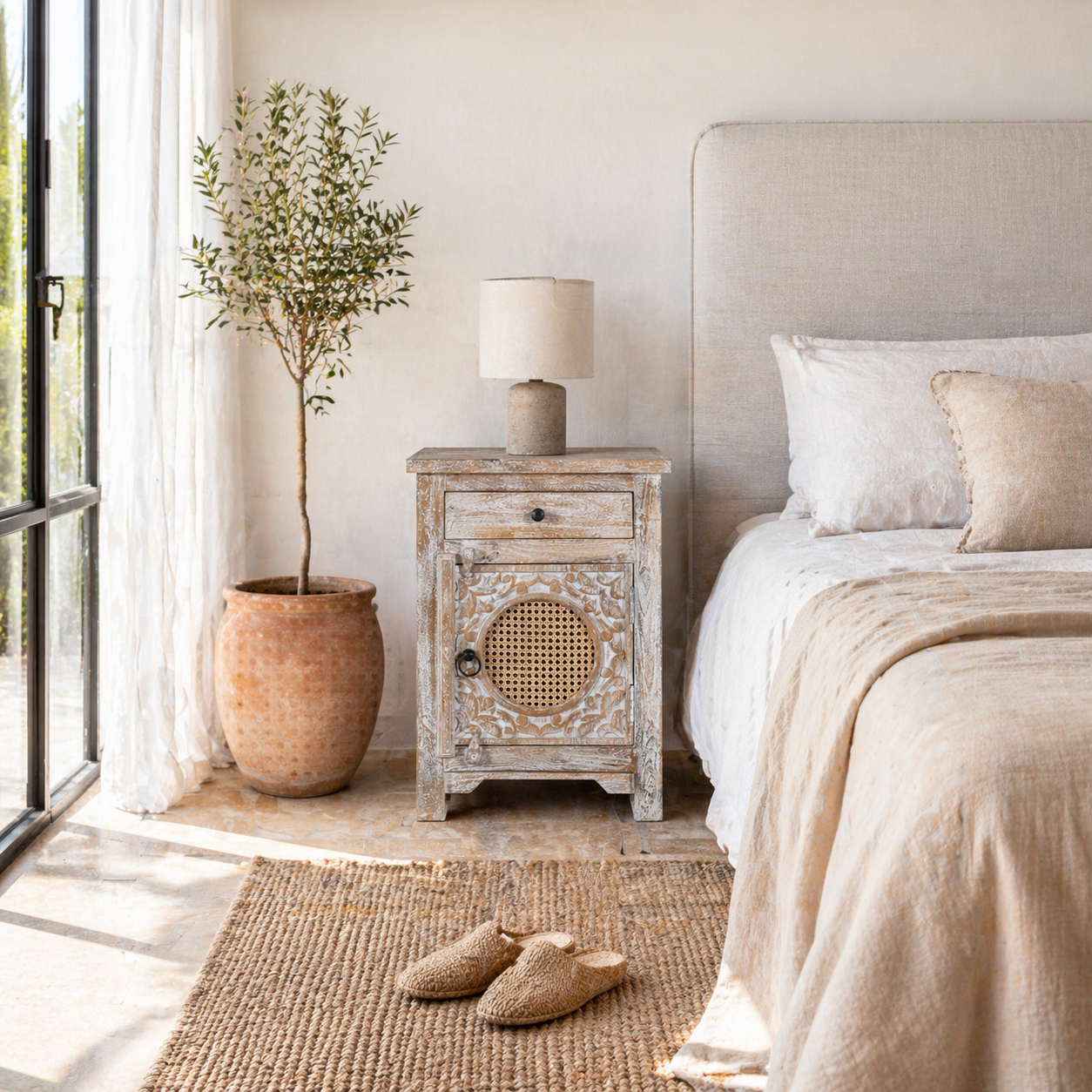 Lifestyle inspiration of a hand carved mango wood night stand with rattan inserts; sustainable bedroom furniture, 67 × 47 × 40 cm.