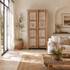 Lifestyle image of a hand carved wooden wardrobe made of solid mango wood with whitewashed floral details; Ibiza-style mango wood wardrobe, 190 × 100 × 40 cm.
