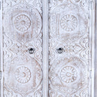Close up image of a white washed hand carved wardrobe made of mango wood in floral design with 2 drawers and ample inside storage.