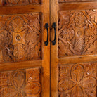Close up image of a dark brown mango wood cabinet with hand carvings, 2 drawers and ample storage.